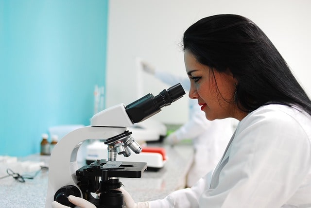 Una mujer científica mirando a través de un microscopio